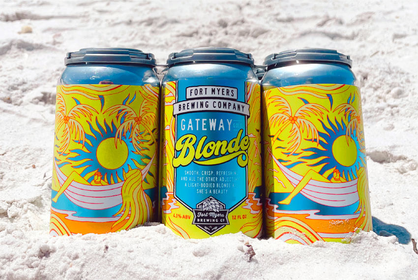 Three cans of beer sitting in the sand.